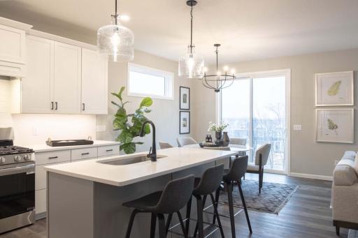 The heart of this kitchen is the stunning island, featuring a sleek quartz countertop that combines beauty and functionality. Photos are from previously built home; options and features may vary.