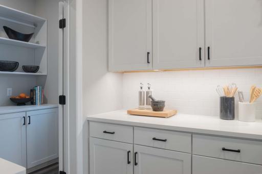 This kitchen features clean white cabinets paired w/bold black cabinet hardware, creating a striking contrast. The combination of light and dark elements adds modern sophistication. Photos are from previously built home; options and features may vary