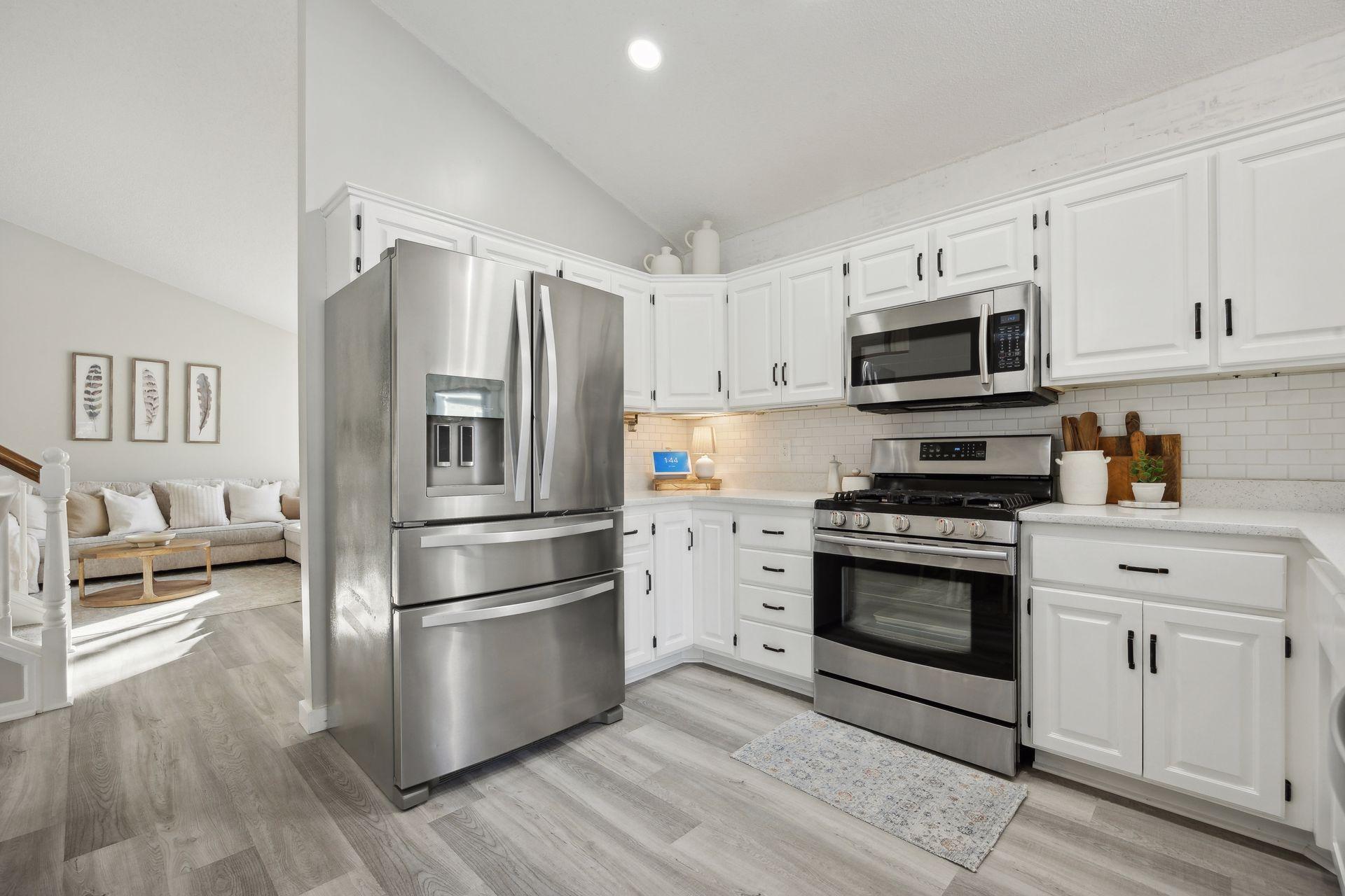 16x12 Main Level Kitchen updated with refaced white cabinetry in 2020, New dishwasher in 2024, new quartz countertops and backsplash, Fresh paint, new flooring, and white trim. North-facing windows and a sliding glass door to the side yard.