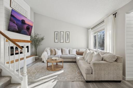 20x20 Main Level Living room with updated styling, Fresh paint, new flooring, white trim and a shiplap-wrapped Electric Fireplace. West-facing windows.