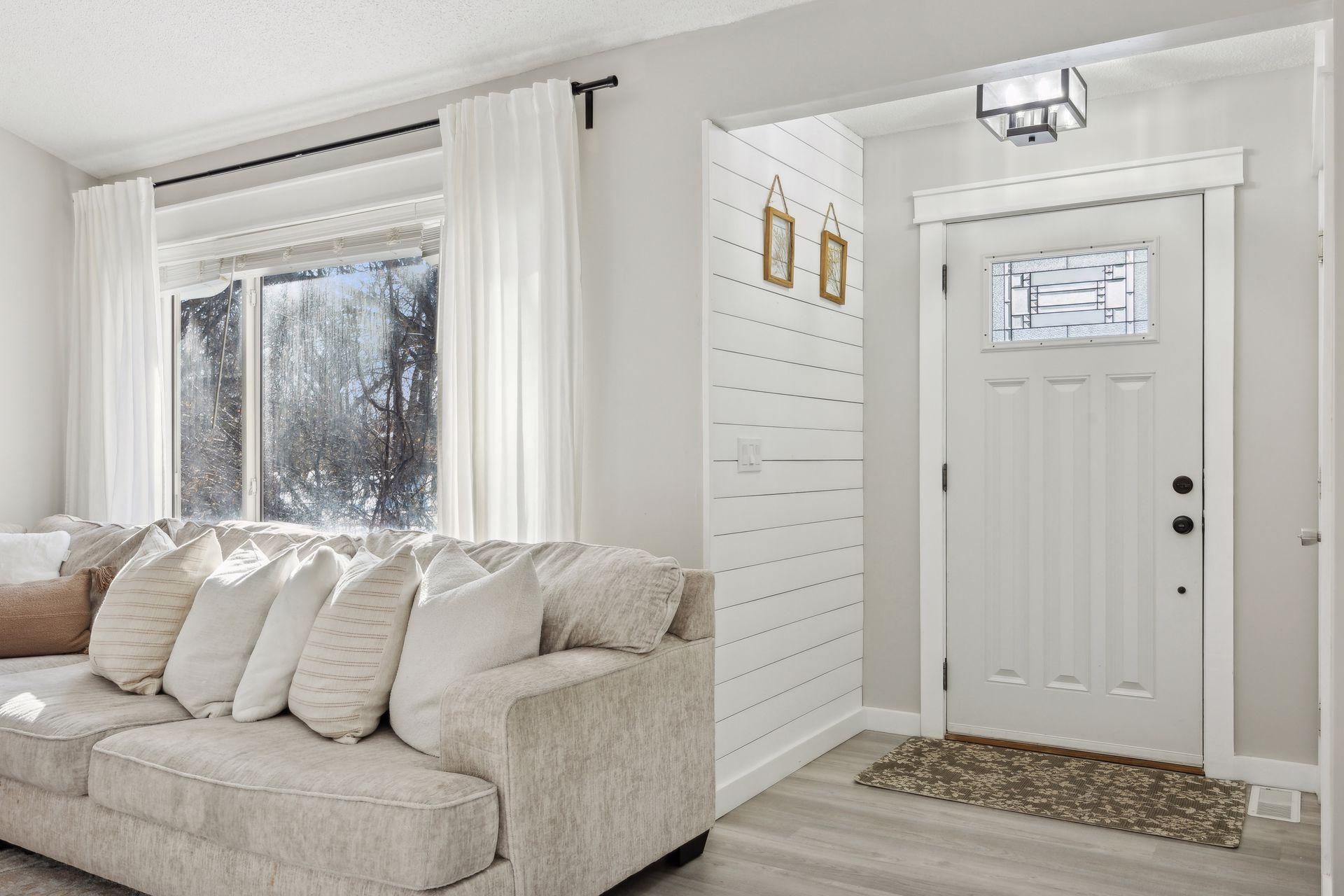 20x20 Main Level Living room with updated styling, Fresh paint, new flooring, white trim and a shiplap-wrapped Electric Fireplace. West-facing windows.