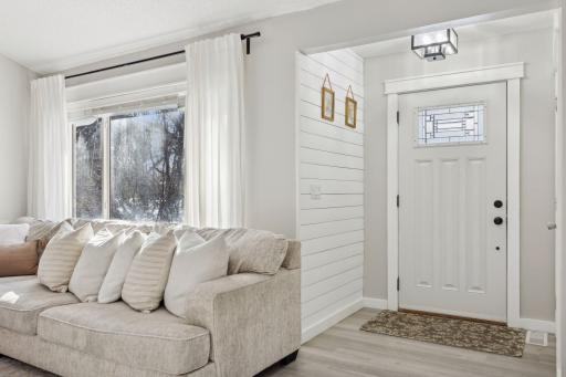 20x20 Main Level Living room with updated styling, Fresh paint, new flooring, white trim and a shiplap-wrapped Electric Fireplace. West-facing windows.