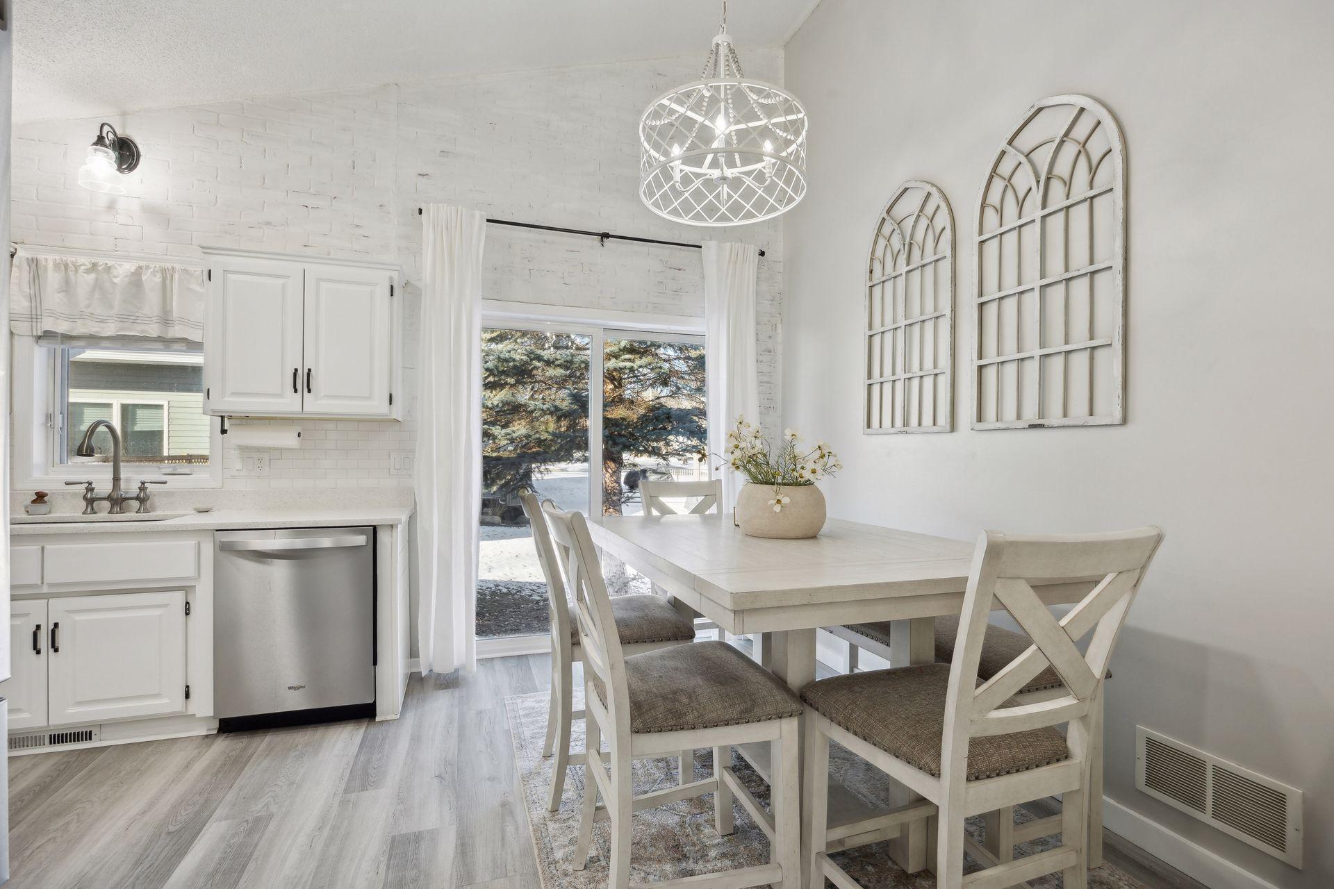 16x12 Main Level Kitchen updated with refaced white cabinetry in 2020, New dishwasher in 2024, new quartz countertops and backsplash, Fresh paint, new flooring, and white trim. North-facing windows and a sliding glass door to the side yard.