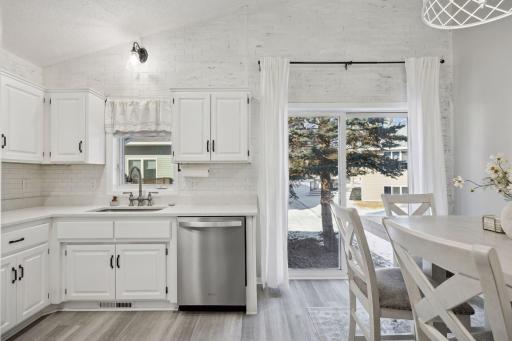 16x12 Main Level Kitchen updated with refaced white cabinetry in 2020, New dishwasher in 2024, new quartz countertops and backsplash, Fresh paint, new flooring, and white trim. North-facing windows and a sliding glass door to the side yard.