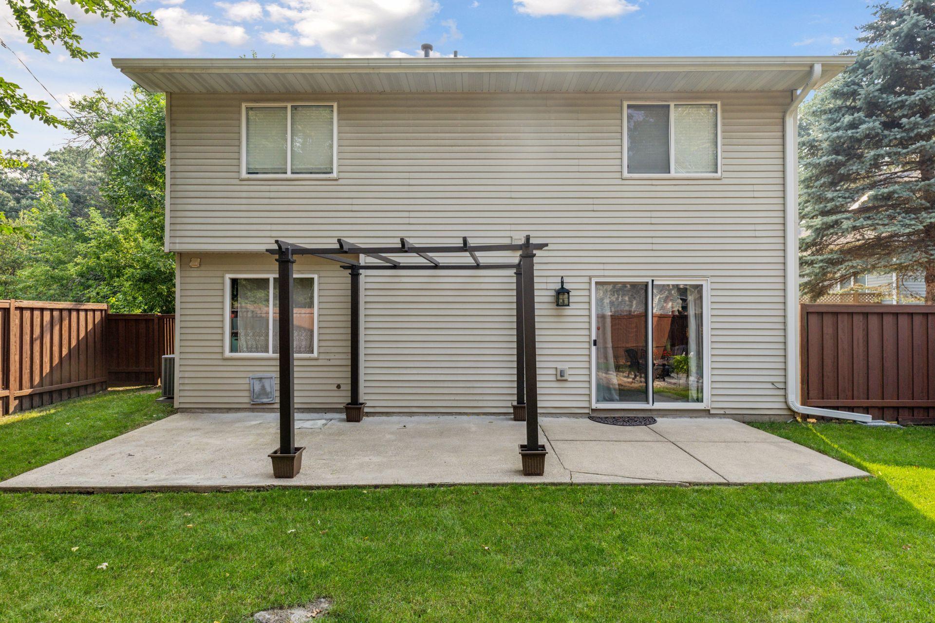 Spacious, fully fenced-in backyard with a concrete patio and additional paver fire pit.