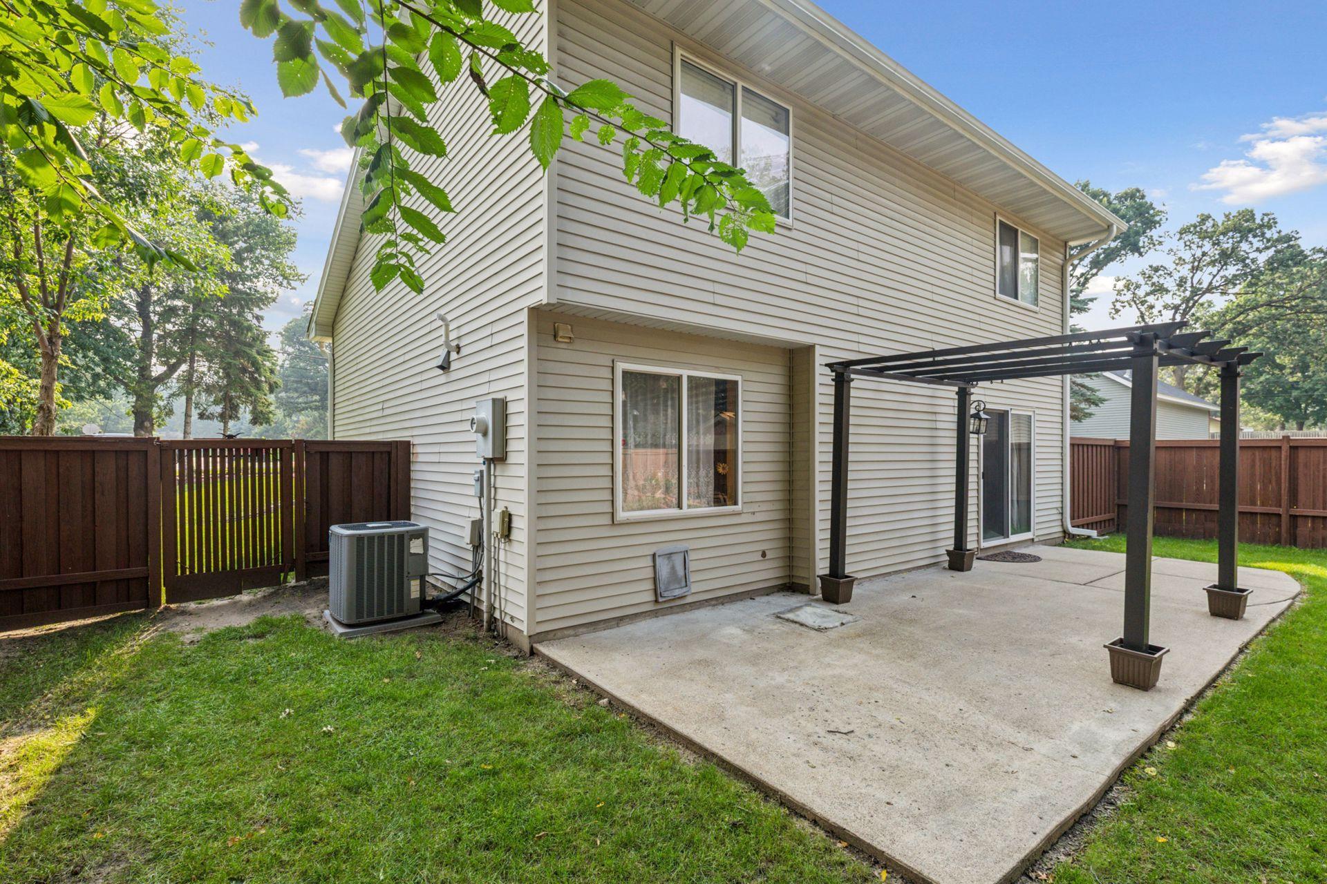 Spacious, fully fenced-in backyard with a concrete patio and additional paver fire pit.