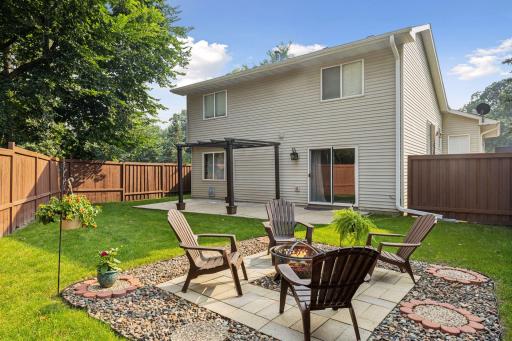 Spacious, fully fenced-in backyard with a concrete patio and additional paver fire pit.