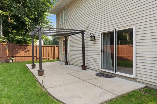 Spacious, fully fenced-in backyard with a concrete patio and additional paver fire pit.