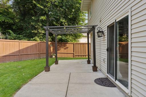 Spacious, fully fenced-in backyard with a concrete patio and additional paver fire pit.
