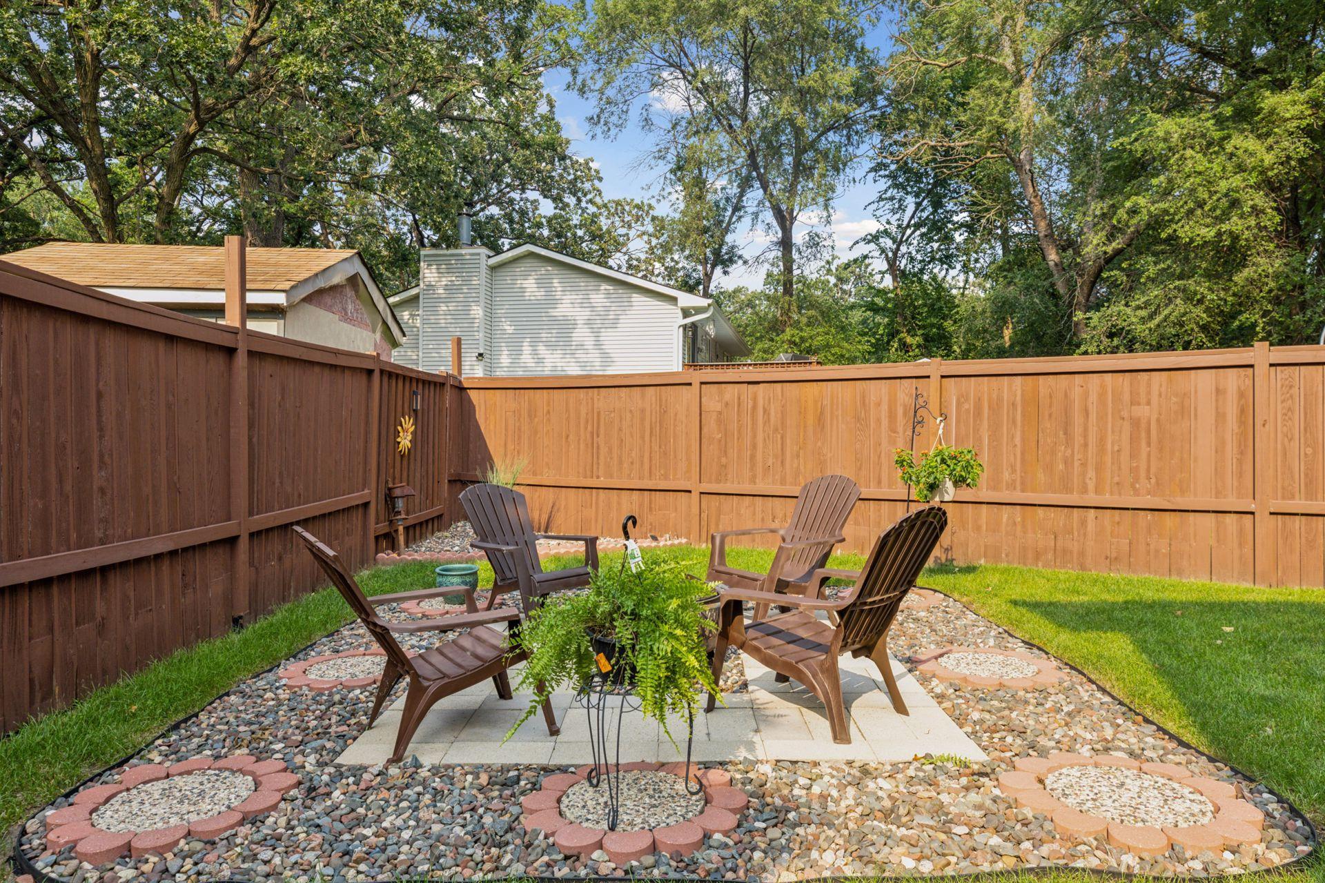 Spacious, fully fenced-in backyard with a concrete patio and additional paver fire pit.