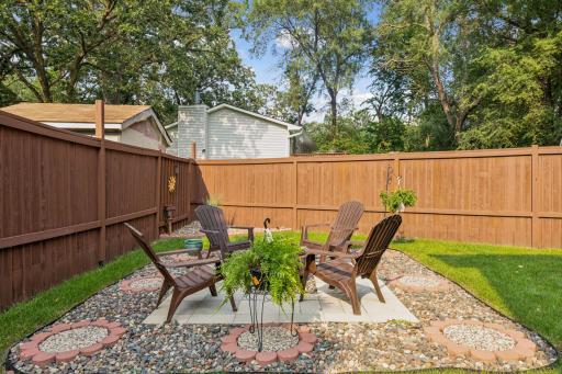 Spacious, fully fenced-in backyard with a concrete patio and additional paver fire pit.