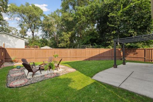 Spacious, fully fenced-in backyard with a concrete patio and additional paver fire pit.