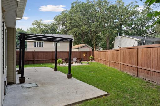 Spacious, fully fenced-in backyard with a concrete patio and additional paver fire pit.
