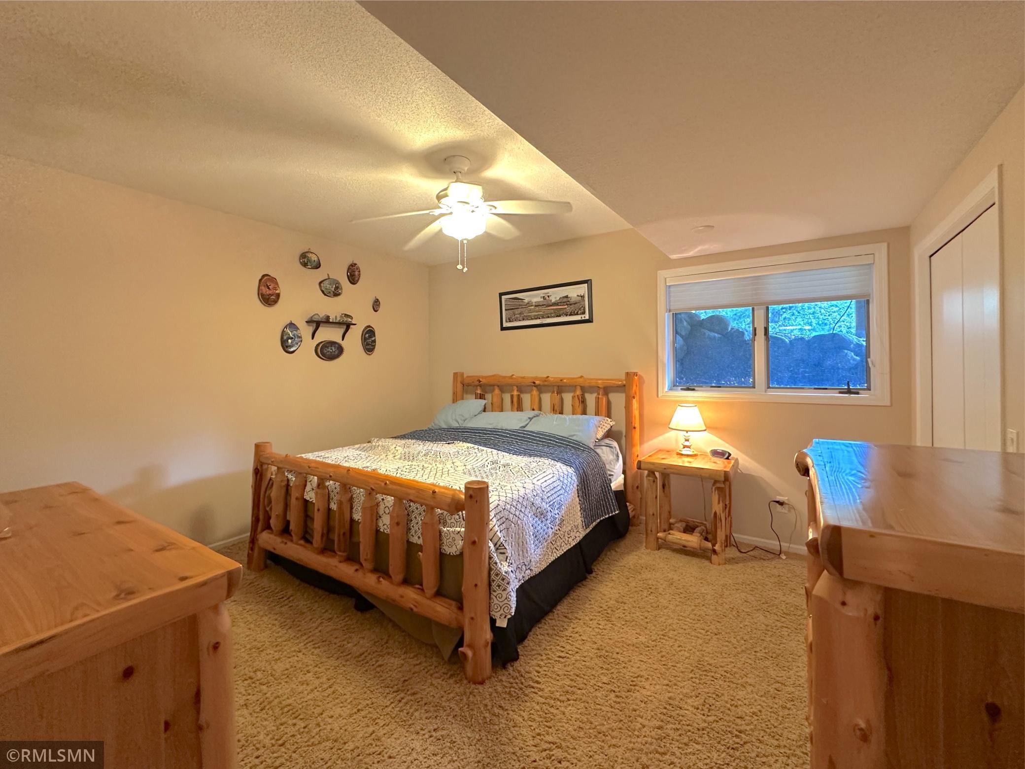 Inviting lower-level bedroom featuring warm neutral tones and a large window brings in wonderful natural light.