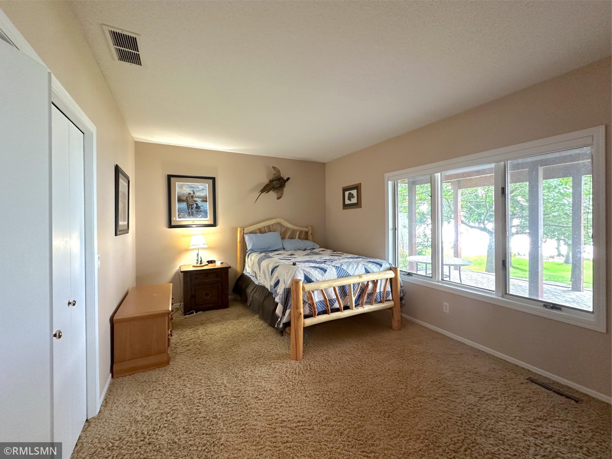Lower-level bedroom featuring large windows that frame peaceful lake views and fill the space with natural light.