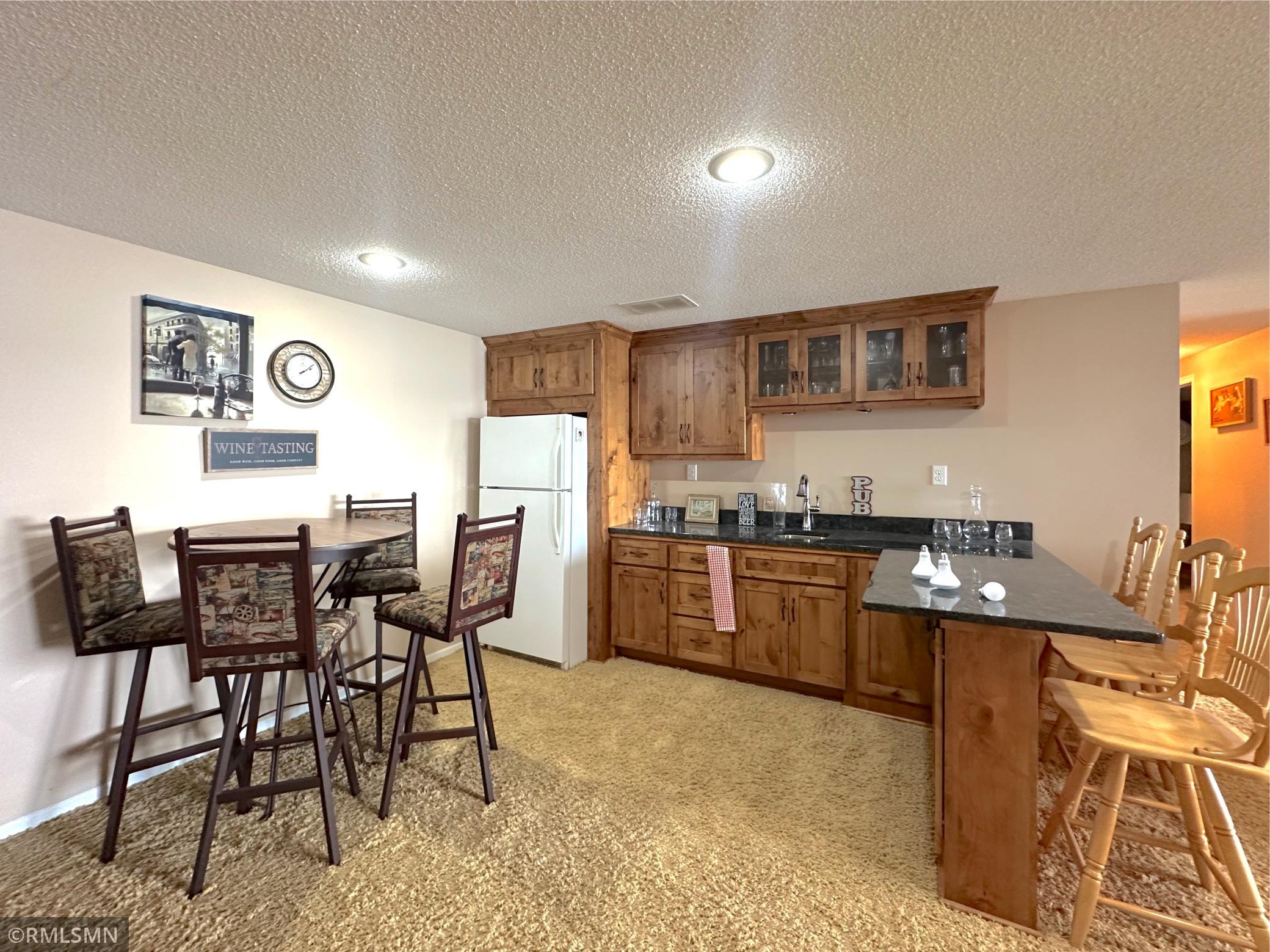 The lower level is made for entertaining, featuring a beautiful wet bar with rich wood cabinetry and bar seating.