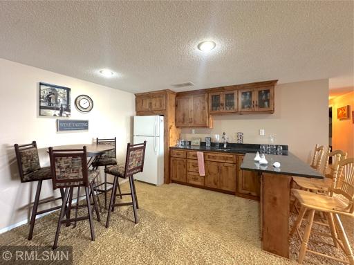 The lower level is made for entertaining, featuring a beautiful wet bar with rich wood cabinetry and bar seating.