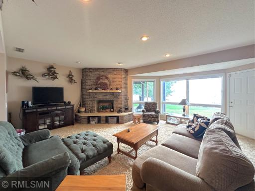 A brick fireplace anchors the space, creating a warm and inviting focal point for gatherings with lakeside views.