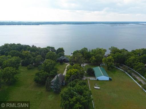 A white fence borders three sides of the property with a tree-lined driveway, adding timeless charm and privacy.