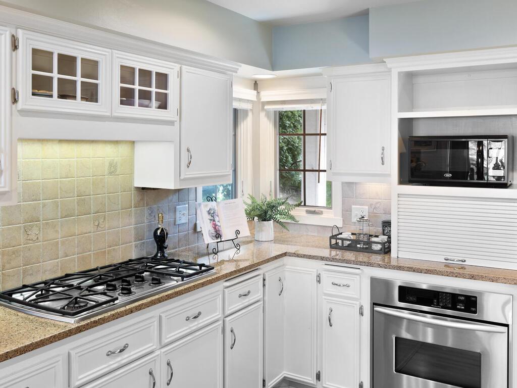 Kitchen has a gas cooktop, stainless steel wall oven, microwave, under counter lighting, corner windows and custom blinds.