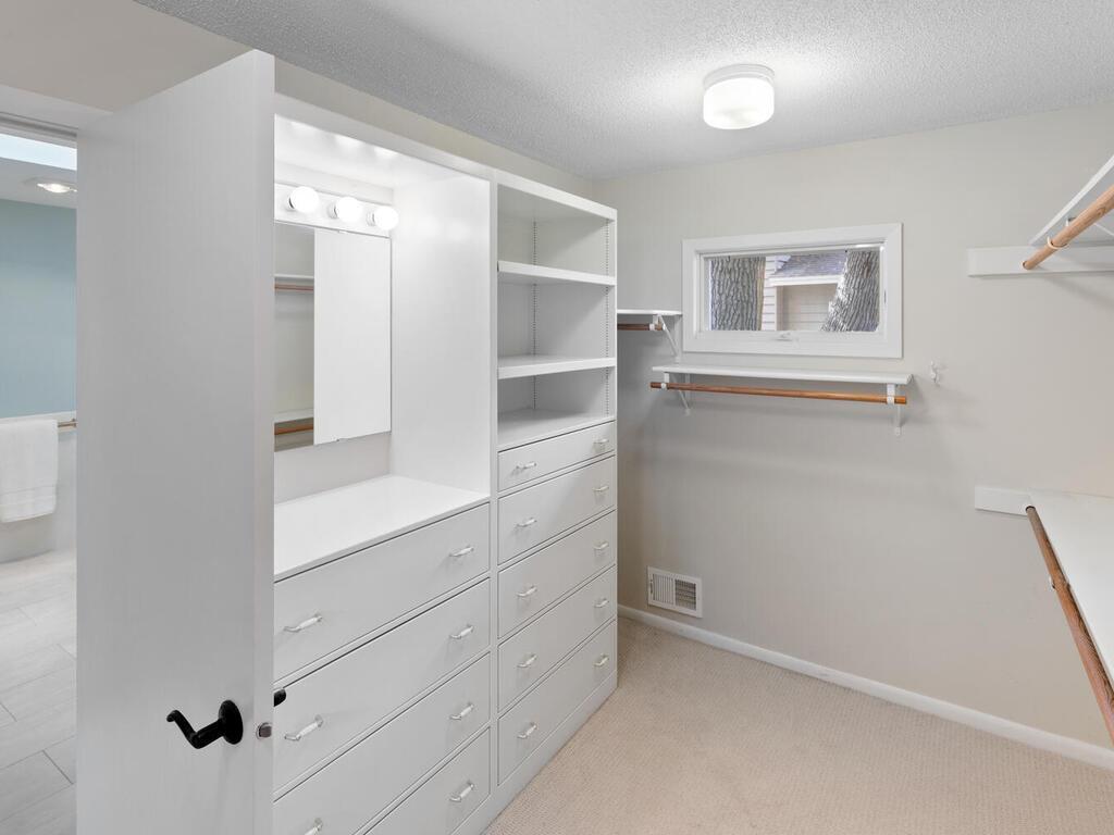 Walk-in closet has lighted mirror and window plus lots of hanging space.