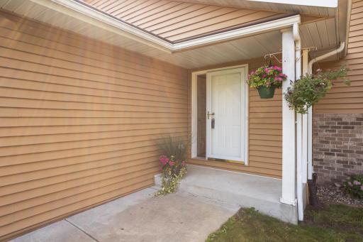 Front entry has an Andersen storm door, concrete walkway and porch.