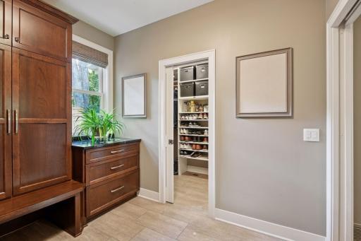 Large walk-in closet with custom shelving and stackable washer and dryer.