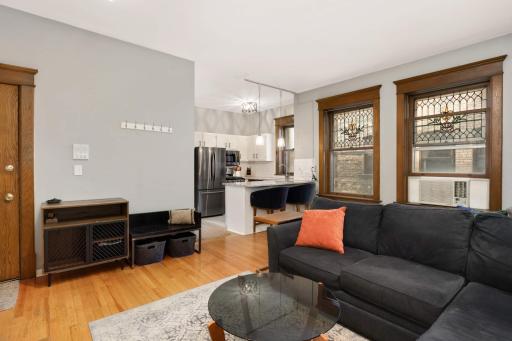 Stylish open-concept living! This bright and airy space features gleaming hardwood floors, original woodwork, and elegant stained-glass windows. The kitchen is updated with stainless appliances, granite countertops, and a breakfast bar perfect for ca