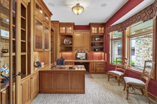 Well appointed office area full of storage and built-ins with natural woodwork with control panel for light and sound system