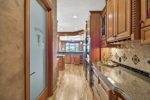 Large walk in pantry has organizers across from the wine and beverage center with extra prep space for entertaining including a wine refrigerator.