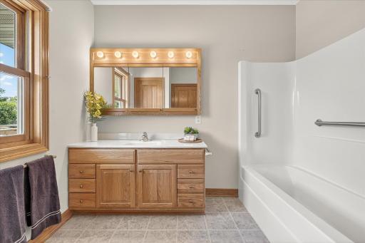 The attached & private primary bath includes tile flooring, a single piece tub/shower surround with grab bars, and a huge oak vanity cabinet. And look at the size of that medicine cabinet!