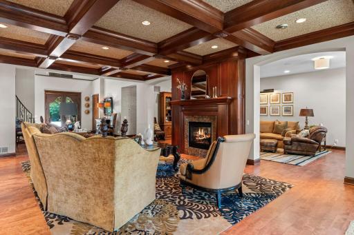 Main living room boasts coffered ceilings, hardwood flooring, gas fireplace, patio access,