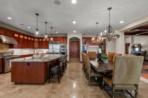 this well appointed kitchen is the ultimate entertainment spot! travertine floor, dark walnut cabinetry, pantry, wine room, wet bar+storage, top of the line appliances, in cabinet+undercounter lighting, new tile backsplash, pot filler, 10' island.