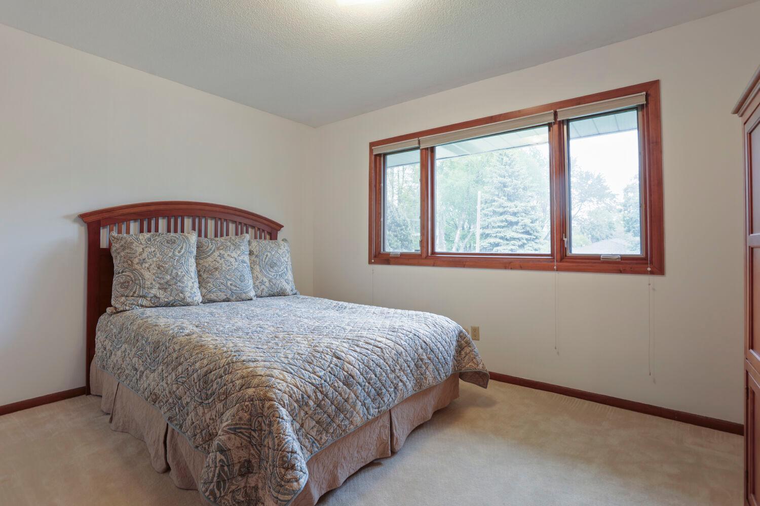 The primary bedroom has a large window drenching the room in natural sunlight.