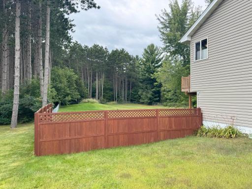 Looking over the fence towards the backyard surrounded by tall trees.