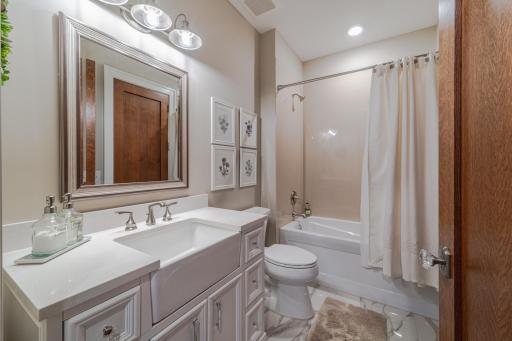 This full bath in the main hall connects with the second bedroom and has a vanity with a farm style sink.
