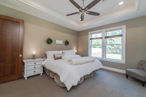 The main floor primary bedroom has large windows, a tray ceiling with a fan and rope lighting set into the crown molding, and a private, full adjoined bath.