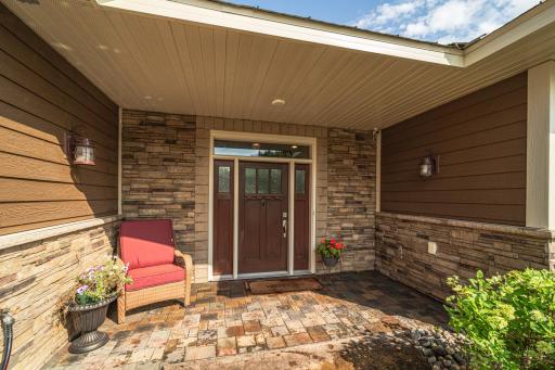 This covered front entry wrapped in stone with sconce lighting is welcoming and provides a shady place to relax.