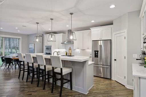 The beautiful kitchen includes quartz countertops, white cabinetry, large center island, walk-in pantry, and a coffee/wine bar.