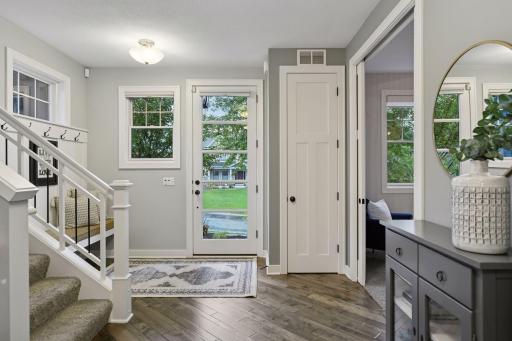 The foyer features a custom built-in bench and leads to the open living spaces with hand-scraped hardwood floors.