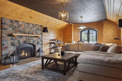 The lower level family room providing a cozy feel with natural woodwork, a painted ceiling, and a gas fireplace.