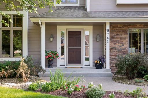 The front entrance features a welcoming covered entry with a beautiful solid wood door, adding both charm and durability.