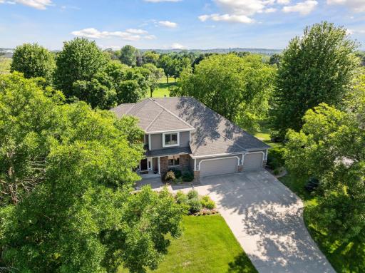 An aerial view showcases the home nestled on a stunning half-acre lot, surrounded by beautiful trees and meticulous landscaping. Just look at this amazing lot!