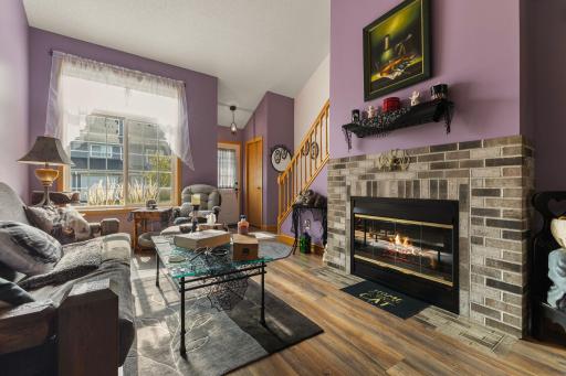 The living room where soaring vaulted ceilings create an airy, open feel and natural light pours in through expansive windows. A stunning fireplace anchors the space, offering cozy ambiance.