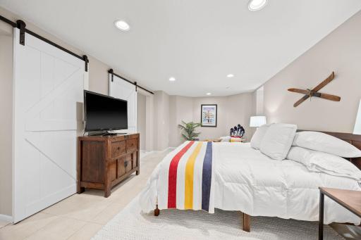 Large private guest bedroom with sliding barn doors adjacent to the family room