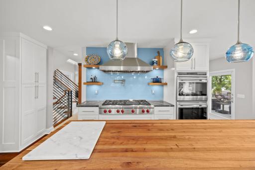 Wolf 6-burner stove top, stylish ventilation hood, glass backsplash & double ovens