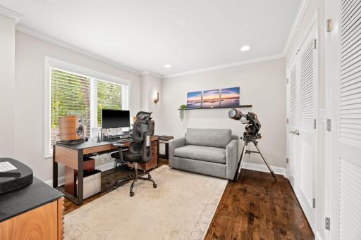 Office/Study main level with wall of custom shelving behind doors keeps the office space clean of office equipment