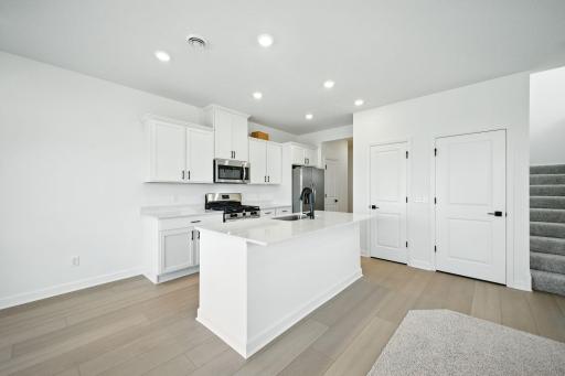 (Photo of an inventory home, actual homes finishes will vary) The stunning kitchen features a large center island, quartz countertops, LVP floors, stainless appliances and more!