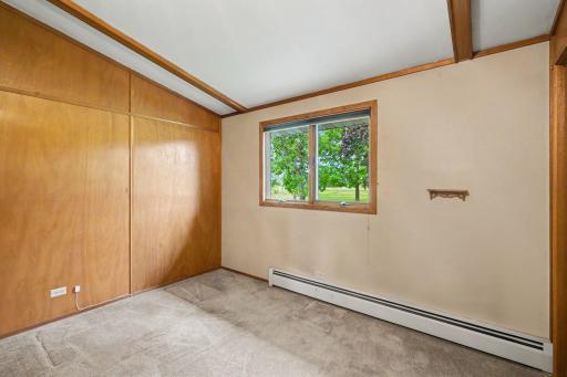 Bright third bedroom on the main level features a classic wood accent beam, generous closet space, and a large window for ample natural light. Complete with excellent closet storage.