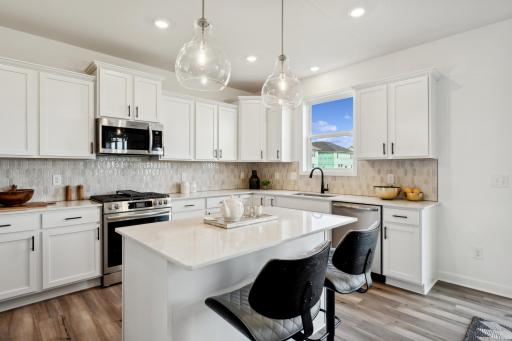 (Photo of decorated model, actual home's finishes will vary) This modern kitchen features a set of brand-new stainless steel appliances, abundant cabinet space and a convenient center island to add seating and counter room.